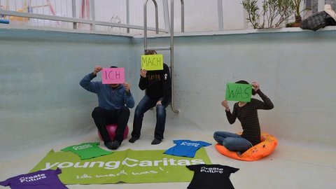 Young Caritas: Drei Personen halten Schilder mit der Aufschrift "Ich", "Mach", "Was"