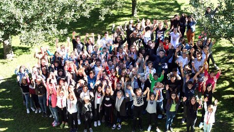 Schüler_innen stehen im Garten und zeigen zum Himmel