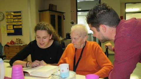 Eine junge Frau liest einer älteren Dame etwas aus einem Buch vor