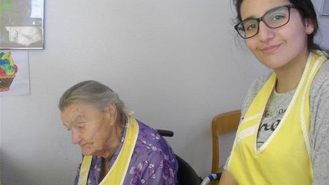 Jugendliche und ältere Frau mit gelben Schürzen