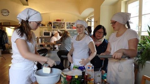 Jugendliche und eine erwachsene Frau bei der Vorbereitung zum Backen