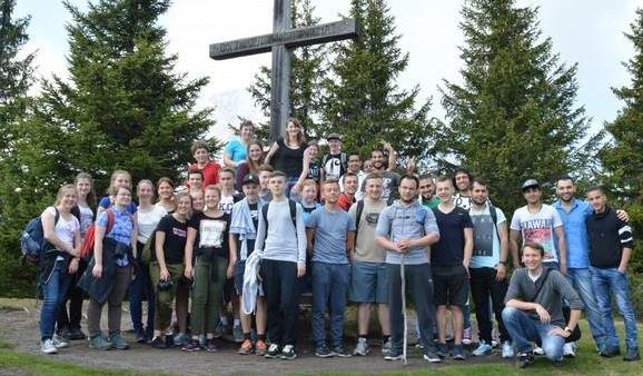 Eine Wandergruppe posiert an einem großen Holzkreuz