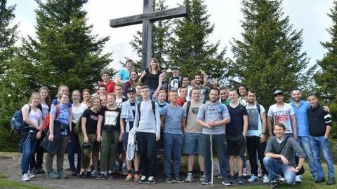 Eine Wandergruppe posiert an einem großen Holzkreuz