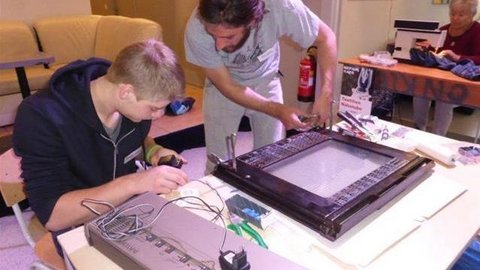 Jugendlicher und Mann beim Reparieren von Elektogeräten