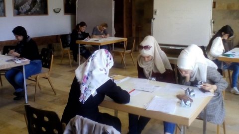 Frauen und Mädchen sitzen an Tischen und lernen