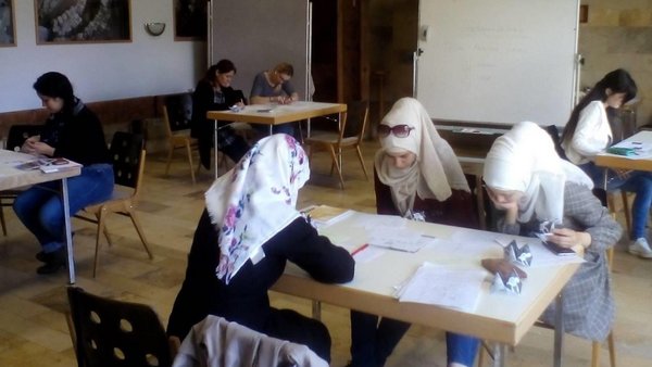 Frauen und Mädchen sitzen an Tischen und lernen