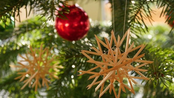 Strohstern mit roter Kugel an Weihnachstbaum