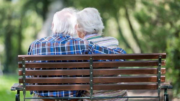 Ein älteres Ehepaar sitzt auf einer Bank im Park 
