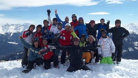 Skigruppe posiert am Berg im Schnee