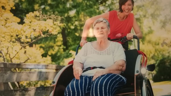 Ältere Frau im Rollstuhl wird von jüngerer Frau geschoben