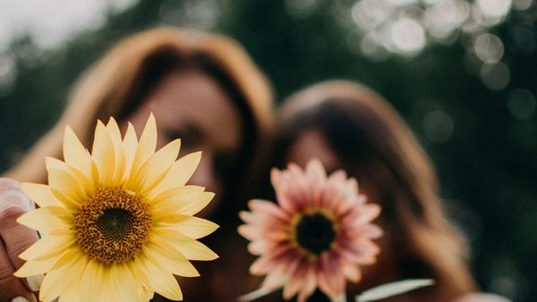Foto Frauen mit Blumen Foto mit zwei Frauen mit zwei Blumen, das Bild ist unscharf, man kann die Frauen nicht erkennen, die Blumen sind im Vordergrund