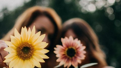 Foto mit zwei Frauen mit zwei Blumen, das Bild ist unscharf, man kann die Frauen nicht erkennen, die Blumen sind im Vordergrund