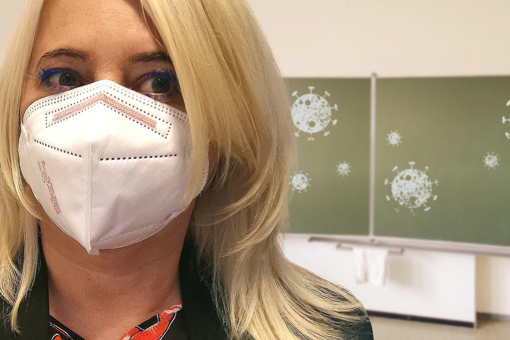 Frau mit Maske steht vor einer Schreibtafel