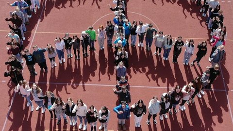 Schüler stheen zu einem PPeacezeichen formiert und schauen in den Himmel