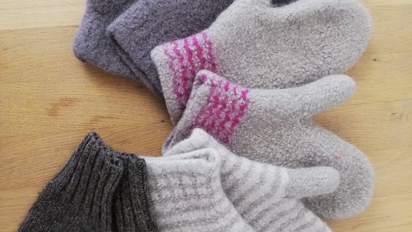 ein Tisch mit selbstgestrickten, bunten Fäustlingen