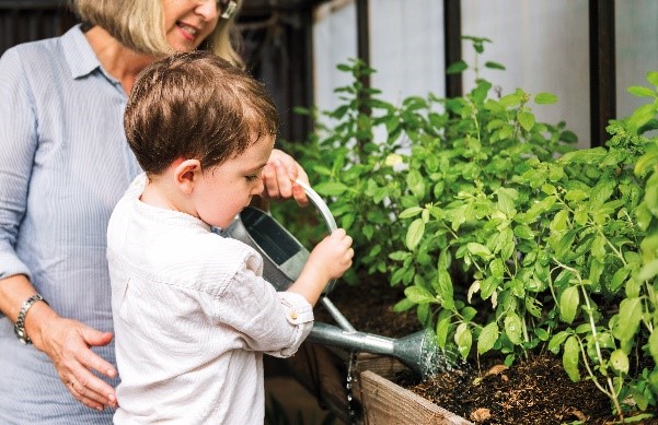 Eine ältere Frau hilft einem kleinen Jungen beim Pflanzengießen